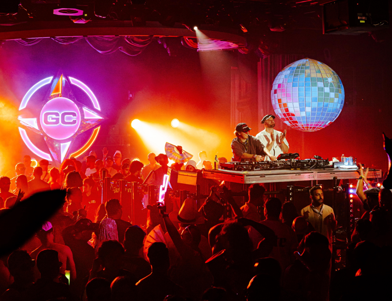 DJ performing on stage with a crowd and disco ball in the background at Groove Cruise, groove cruise family, LS vacations, ENM travel, cruise vacations, bahamas music festival, tropical festival, cruises for alternative community, vacation festival, looking for festival friends, groove cruise fam, GC Fam, wonderfam, meet penny