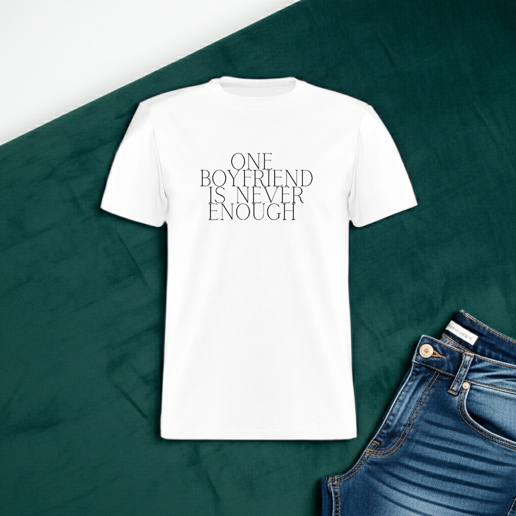 White t-shirt with 'ONE BOYFRIEND IS NEVER ENOUGH' text on a green fabric background with jeans. One Boyfriend Is Never Enough Cropped T-Shirt - white, White cropped tee with minimalist black text that reads “One Boyfriend Is Never Enough,” worn by a confident woman with a sassy attitude. adult humor tees, lifestyle, alternate lifestyles