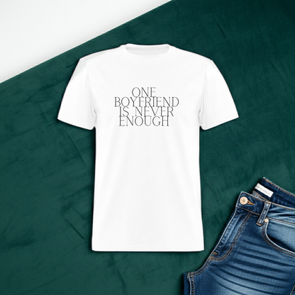 White t-shirt with 'ONE BOYFRIEND IS NEVER ENOUGH' text on a green fabric background with jeans. One Boyfriend Is Never Enough Cropped T-Shirt - white, White cropped tee with minimalist black text that reads “One Boyfriend Is Never Enough,” worn by a confident woman with a sassy attitude. adult humor tees, lifestyle, alternate lifestyles